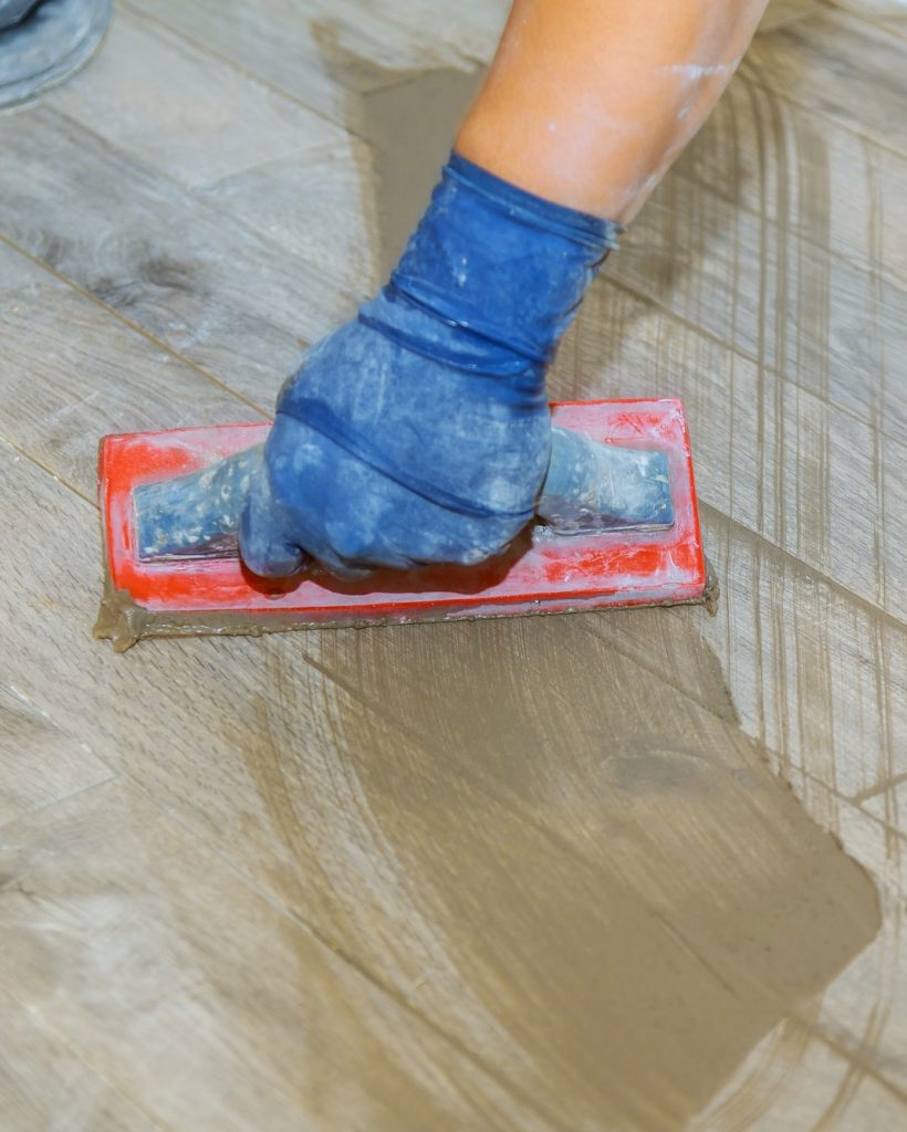 hand-of-flooring-on-gray-color-of-new-grout-tile-on-tile-gray-for-the-final-step-for-flooring.jpg